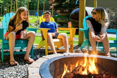 two girls and a boy sitting around a fire pit at Sleeps 14 Pool Hot Tub Sauna Pickleball Arcade in Stroudsburg