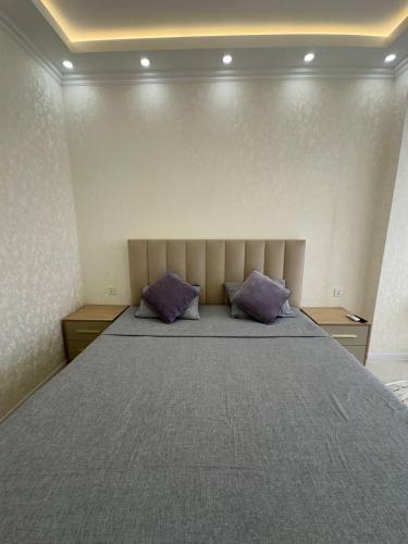 a bedroom with a large bed with two purple pillows at Al-Beruni 4 in Dushanbe