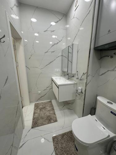 a white bathroom with a toilet and a sink at Al-Beruni 4 in Dushanbe
