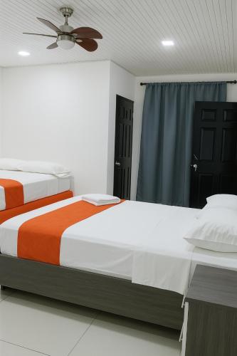 two beds in a bedroom with a ceiling fan at Hotel Milan Costa Rica in San José
