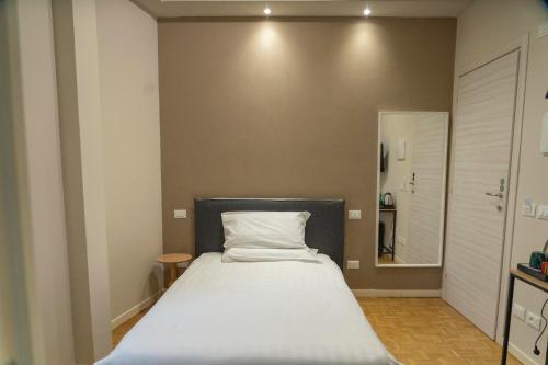 a bedroom with a large bed with a white pillow at Giardini Rooms in Cremona