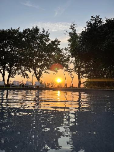 a pool of water with trees in front of a sunset at Casa da Fonte de Cima in Celorico de Basto