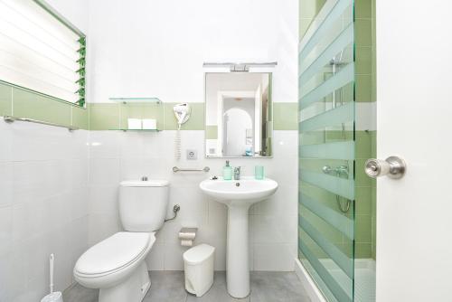 a white bathroom with a toilet and a sink at Los Veleros Apartments in Puerto Rico de Gran Canaria