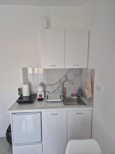 a small kitchen with white cabinets and a sink at Airport Apartmani Nevena in Mitrovići
