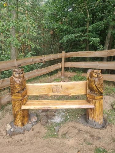 a wooden bench with two statues of cats on it at 02 JURTA hnědá v jablečném sadu 