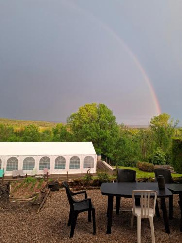 a table and chairs with a rainbow in the background at Auberge du tilleul chambres de campagne dans la région lacs et cascades 