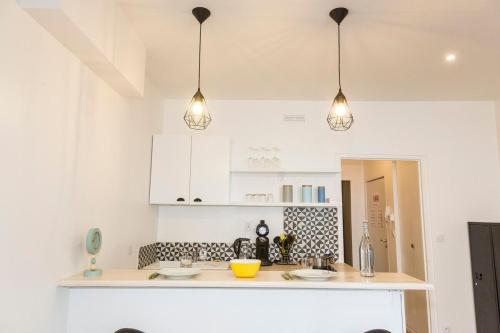 a kitchen with white cabinets and three pendant lights at L'escale - Centre ville - 3 étoiles in Bourg-en-Bresse