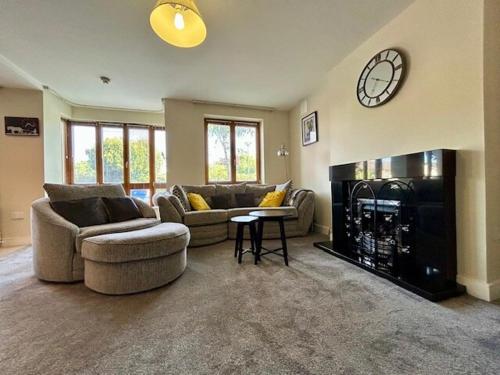 a living room with two couches and a clock above a fireplace at My Kilkenny Stay - walk to city centre in 5 mins in Kilkenny