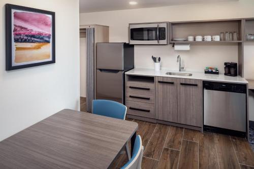 a kitchen with stainless steel appliances and a table at Home2 Suites By Hilton Clearwater St. Petersburg Ulmerton Rd in Clearwater