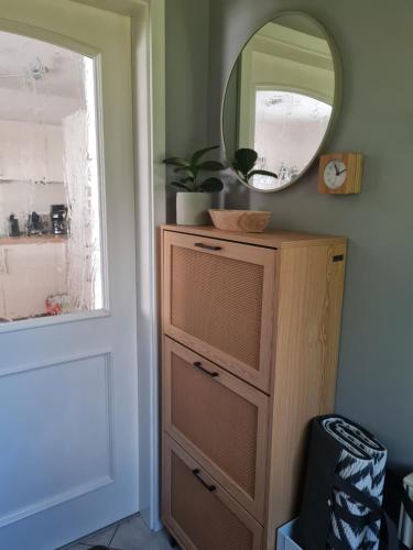 a dresser with a mirror next to a door at DAS kleine Haus in Wandlitz