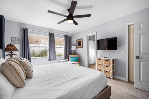 a bedroom with a white bed with a ceiling fan at Canal Front Beach Home, Private Pool in Flagler Beach