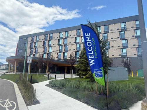 a building with a blue and green flag in front of it at Residence & Conference Centre - Kelowna in Kelowna