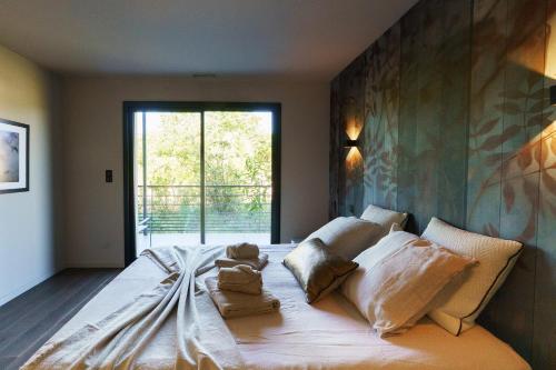 ein Schlafzimmer mit einem großen Bett mit einem großen Fenster in der Unterkunft MAISON CHAPRON Villa de standing avec piscine, calme et golf à Biscarrosse in Biscarrosse