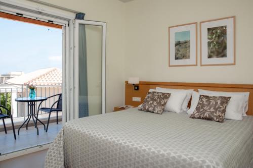 a bedroom with a bed with a view of a balcony at Hotel Estia in Finikounta