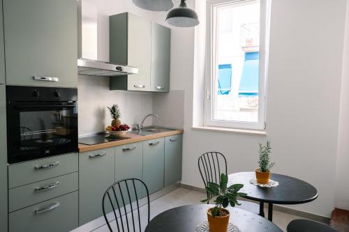 a kitchen with white cabinets and a table with chairs at Domus Picena - Suites & Relax in Grottammare