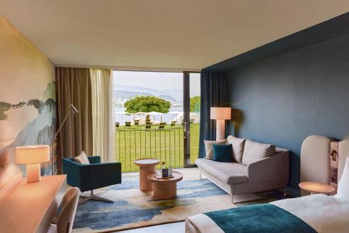 a hotel room with a bed and a living room at HERMITAGE Lake Lucerne - Beach Club & Lifestyle Hotel in Luzern