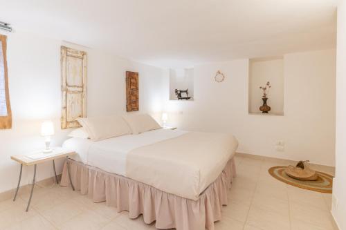 a white bedroom with a large bed and a table at La Casèdde in Cisternino