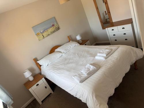 a bedroom with a bed with white sheets and pillows at The Bell Hotel Cottages in Burgh le Marsh