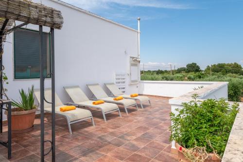 a patio with white chairs on a roof at La Casèdde in Cisternino