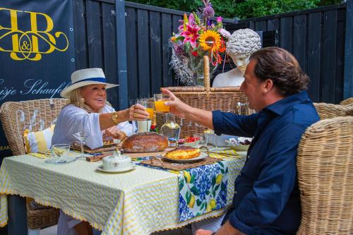 a man giving a woman a glass of orange juice at a table at B&B Huisje Schaufeli in Apeldoorn