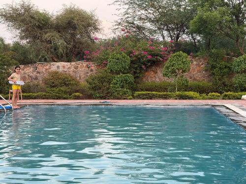 a person standing next to a swimming pool at Soul Tree Retreat in Bhundsi