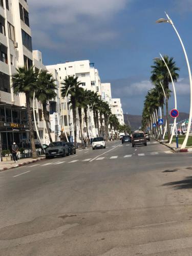 a city street with palm trees and cars on the road at Vacancia in Martil