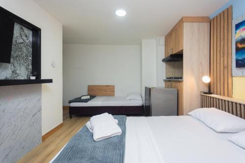 a small room with two beds and a refrigerator at Hotel Lares 70 Laureles in Medellín