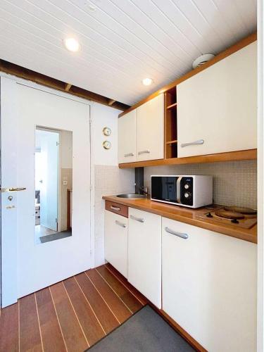 une cuisine avec des armoires blanches et un micro-ondes dans l'établissement Résidence Casino - Studio 2 personnes proche plages à Lacanau Océan MAE-0411, à Lacanau