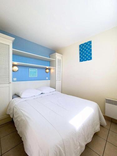 une chambre avec un grand lit blanc avec une tête de lit bleue dans l'établissement Résidence Bleu Marine - Appartement vue mer 4 personnes, résidence avec piscine, Lacanau Océan MAE-0461, à Lacanau