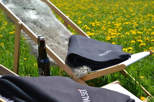 a rocking chair with a blanket and a bottle of wine at Schnider Bed&Breakfast und Café in Vals