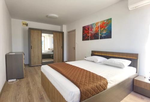a bedroom with a bed and a painting on the wall at Cabacum Pleasure Beachfront Apartments in Varna City