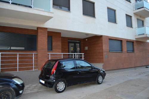 un pequeño coche negro estacionado frente a un edificio en Star Apartman, en Vranje