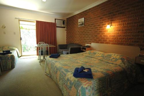 een hotelkamer met een bed en een bakstenen muur bij Burra Motor Inn in Burra