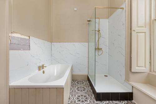 a bathroom with a shower and a tub and a sink at The Chapel Suite in Marske