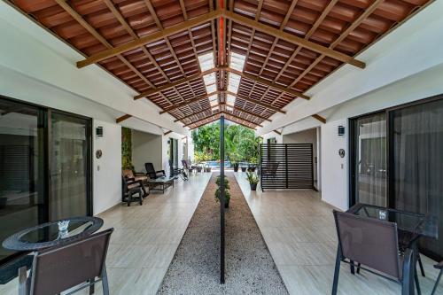 an open lobby with tables and chairs and a ceiling at Las Perlitas Rentals Playa Samara in Sámara