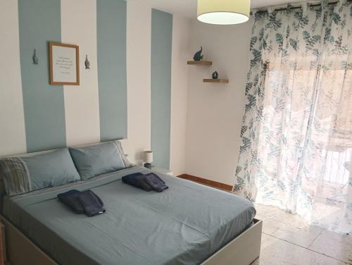 a bedroom with a bed with blue sheets and a window at Limpida Casa Vacanza in San Nicola Arcella