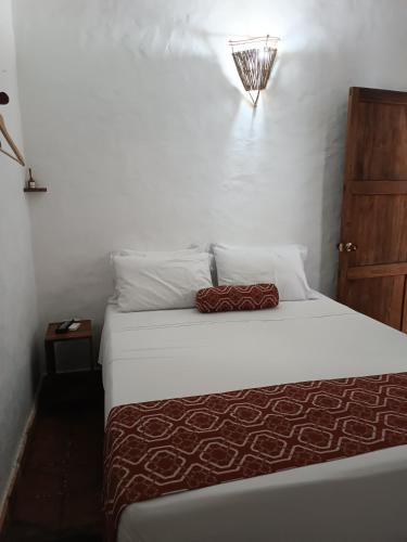a bedroom with a bed with white sheets and pillows at MONCOGUA Casa de Hospedaje in Barichara