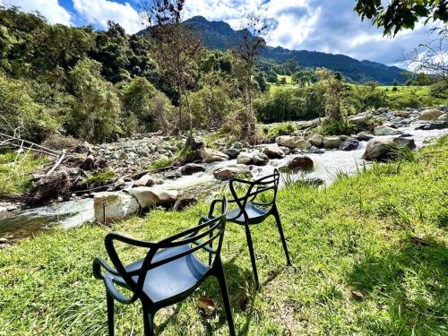 two chairs sitting in the grass next to a river at Heated & Cozy Cabin in Nature in Cuenca