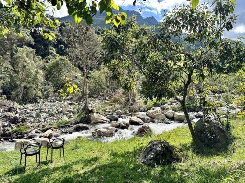 two chairs sitting in front of a river with rocks at Heated & Cozy Cabin in Nature in Cuenca