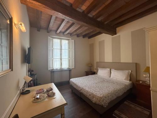 a bedroom with a bed and a table and two windows at Il Cortiletto in Piacenza