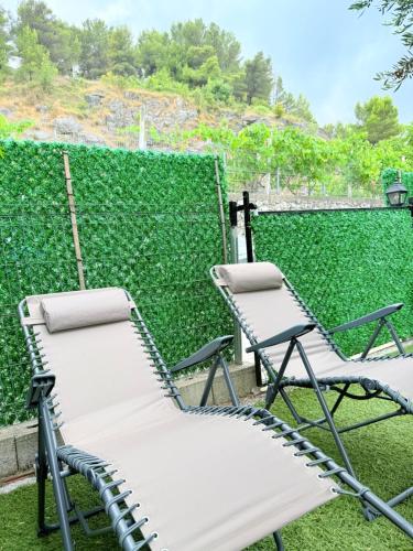 two chairs sitting on a patio with a green hedge at 446 Tiny House Shirokë in Široka