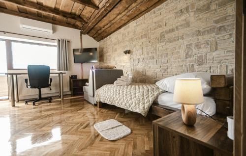 a bedroom with a stone wall with a bed and a desk at Lovely Home In Lepoglava With Sauna in Lepoglava