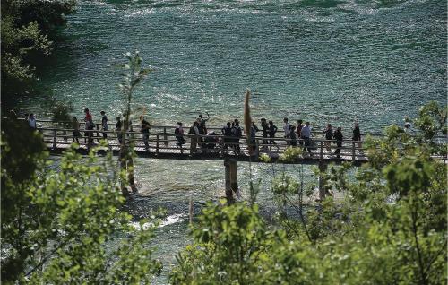 a group of people walking across a bridge over the water at 3 Bedroom Awesome Home In Badanj in Drniš