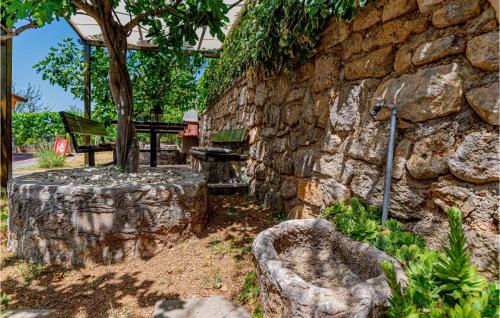 a stone wall with a bench and a tree at 3 Bedroom Awesome Home In Badanj in Drniš