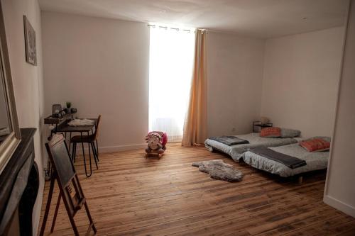 a bedroom with two beds and a table and a window at Maison centre Hennebont in Hennebont