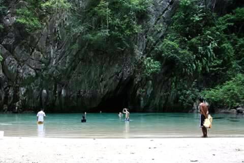 a group of people standing in the water at a beach at Cashew Nut Bungalow, Ko Mook in Koh Mook