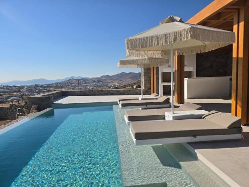 a swimming pool with lounge chairs and an umbrella at Mystic Heaven in Mýkonos City
