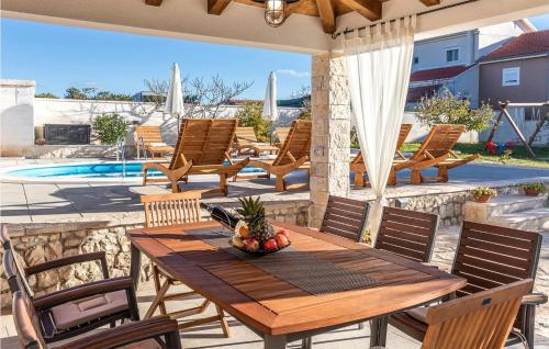 a patio with a wooden table and chairs and a pool at Luxurious Home In Vrsi in Vrsi