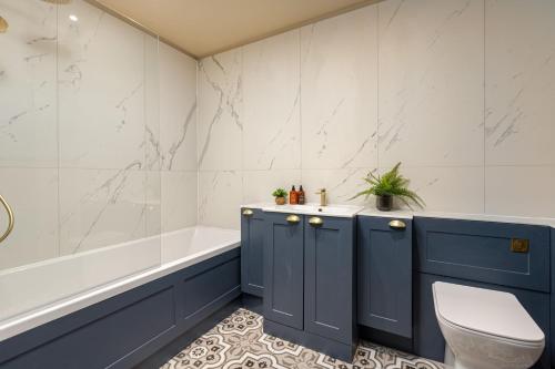 a bathroom with blue cabinets and a tub and a toilet at The Library Suite in Marske