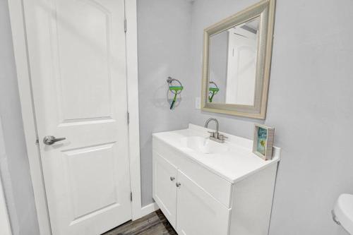 a white bathroom with a sink and a mirror at The Dolphin Watch Near the Beach in FWB - Unit 7 in Fort Walton Beach